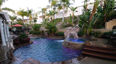 Lit up outdoor pool and jacuzzi with a serene green view. Photo