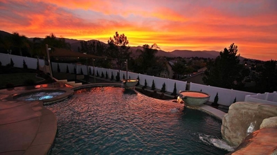 Shot of pool and jacuzzi with orange sunset view. Photo
