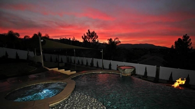 Shot of pool and jacuzzi with orange sunset view. Photo