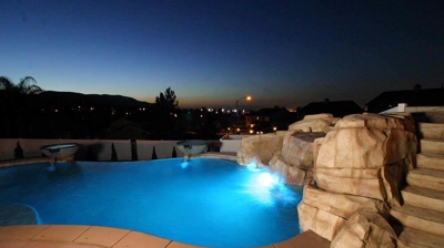 lit up pool in the night time with gorgeous landscape of stones. Photo