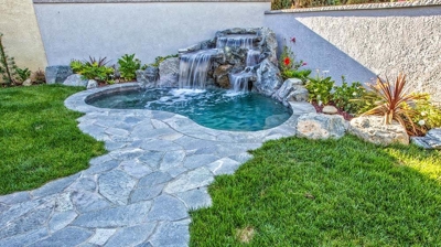 Serene backyard oasis featuring a cascading waterfall and natural stone accents. Photo