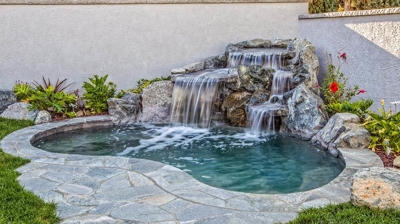 Zen-inspired backyard spa oasis adorned with a tranquil waterfall and rocky features. Photo