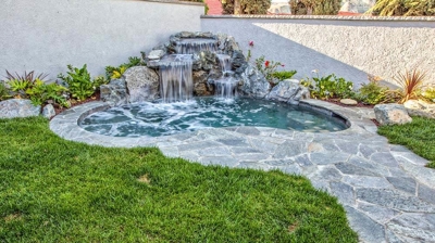 Peaceful outdoor haven boasting a cascading waterfall and organic stone embellishments. Photo