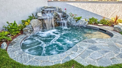 Calming outdoor retreat adorned with a graceful waterfall and rugged rock features. Photo