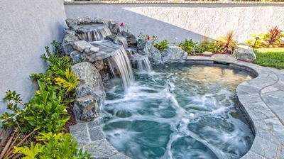 Enchanting backyard hideaway featuring a tranquil waterfall and verdant greenery. Photo