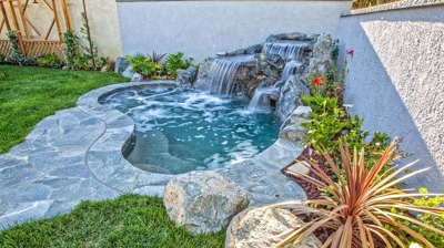 Scenic backyard oasis with a cascading waterfall and harmonious blend of stone and grass. Photo