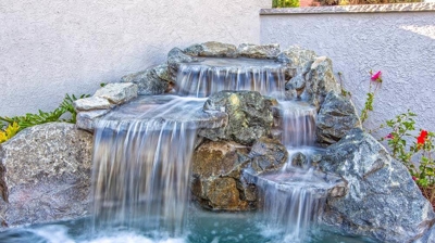 Blissful outdoor spa retreat complete with a soothing waterfall and rocky textures. Photo