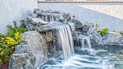 Naturalistic backyard sanctuary featuring a picturesque waterfall and lush vegetation. Photo