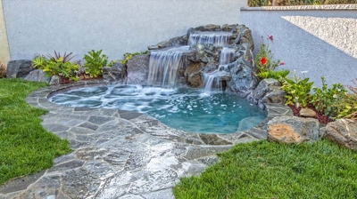 Relaxing backyard sanctuary with a picturesque waterfall and rustic stone elements. Photo