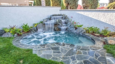 Idyllic backyard paradise with a stunning waterfall centerpiece and natural stone details. Photo