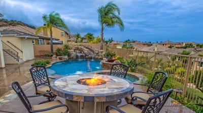Island-inspired backyard sanctuary a pool and spa next to a fire pit. Photo