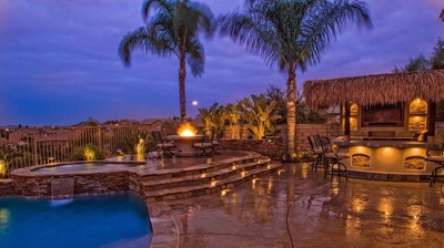 Exotic island-themed backyard paradise featuring a pool, spa, and fiery accents. Photo