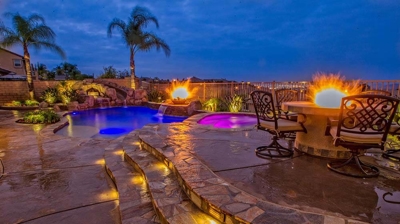 Tranquil backyard sanctuary inspired by tropical islands, complete with pool, spa, and fire features. Photo