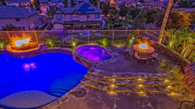 Enchanting island-themed outdoor haven complete with pool, spa, fire elements, and outdoor kitchen. Photo