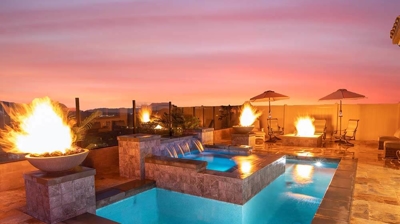 Outdoor oasis with pool, raised spa, cascading waterfall, and fiery ambiance. Photo