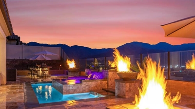 Backyard pool escape with a pool and spa surrounded by fire features to keep warm. Photo