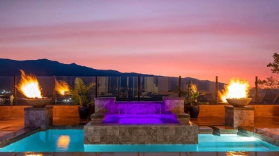 Backyard pool with elevated spa, waterfall, and surrounding fire features. Photo