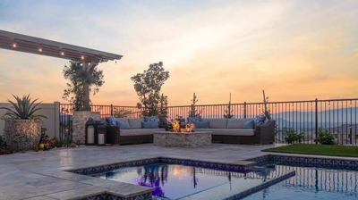 Poolside haven featuring spa, lounge chairs, and captivating sunset views. Photo