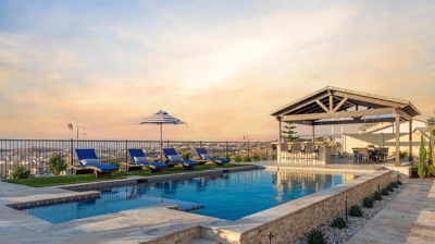 Backyard paradise with pool, spa, loungers, and enchanting sunset panoramas. Photo