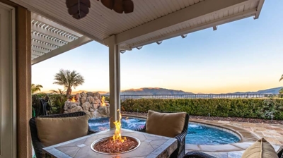 Conversation seating area with fire pit overlooking a pool. Photo