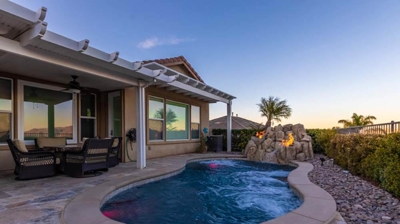 Backyard sanctuary boasting a pool complemented by a rock formation waterfall and flickering fire. Photo
