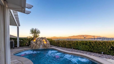 Secluded backyard oasis featuring a pool, hedge perimeter, and a cascading waterfall. Photo