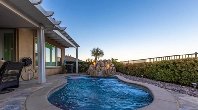 Private backyard retreat showcasing a pool enclosed by hedges, adorned with a rock waterfall. Photo