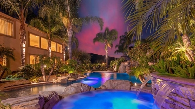 Serene tropical retreat with palm tree surroundings, showcasing a blue-lit pool. Photo