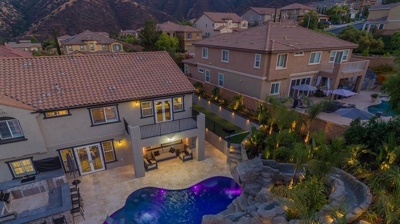 Aerial shot of lit up blue pool in backyard with overhead lights. Photo