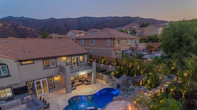 Aerial shot of lit up blue pool in backyard with overhead lights. Photo