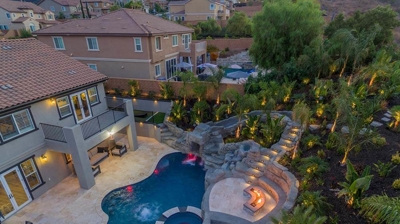 Aerial shot of pool in backyard with overhead lights. Photo