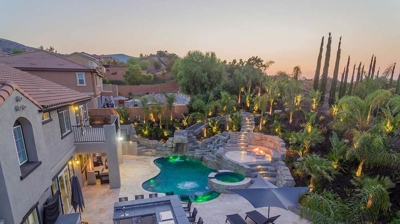Aerial shot of pool in backyard with overhead lights. Photo