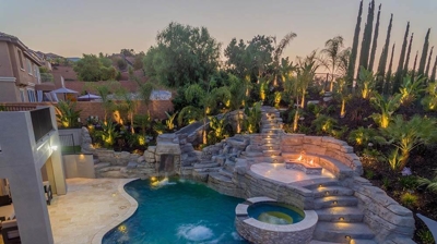 Aerial shot of pool in backyard with overhead lights. Photo