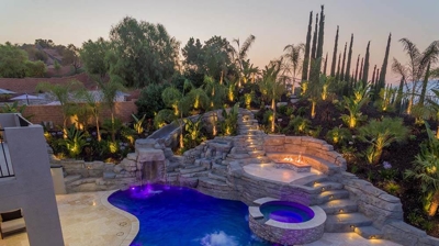 Aerial shot of lit up blue pool in backyard with overhead lights. Photo