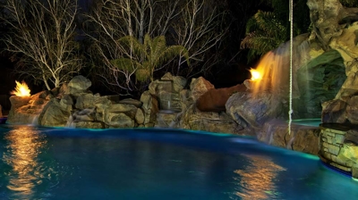 Custom freeform pool at night with fire features Photo