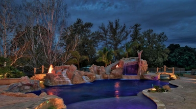 Custom freeform pool with stone details at night Photo