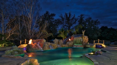 Custom freeform pool with stone details illuminated at night Photo