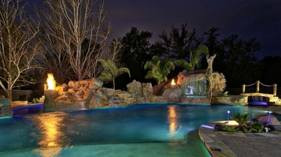 View of custom pool with fire and water features at night Photo