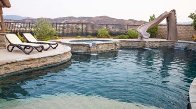 Backyard pool with spa, slide, tanning ledge, and poolside seating Photo