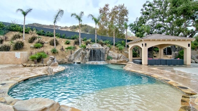 Beautiful pool with slide and waterfall feature over spa Photo