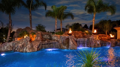Backyard pool at twilight with waterfall and fire bowl features Photo