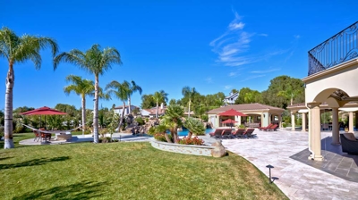 Backyard with hammock, pool, firepit, and kitchen under patio Photo