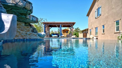 Backyard swimming pool with patio lounge area Photo