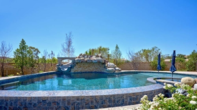 Pool with umbrella covered area and jacuzzi Photo
