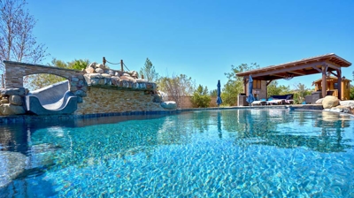 Stunning backyard pool with slide and patio lounge area Photo