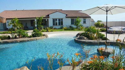 Gorgeous white home in the summer with refreshing pool and umbrella overhead Photo