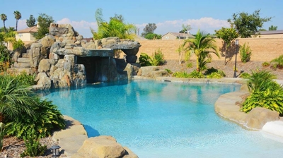 Lounging waterfall area with seating area and ocean-like pool oasis Photo