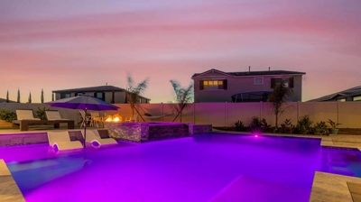White pools chairs nestled within purple lit pool on a summer night Photo