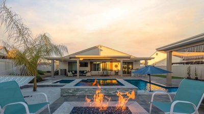 A lit fire within the fireplace in the lounging section of backyard Photo