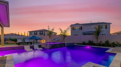 Purple lighting in backyard pool with modern homes Photo